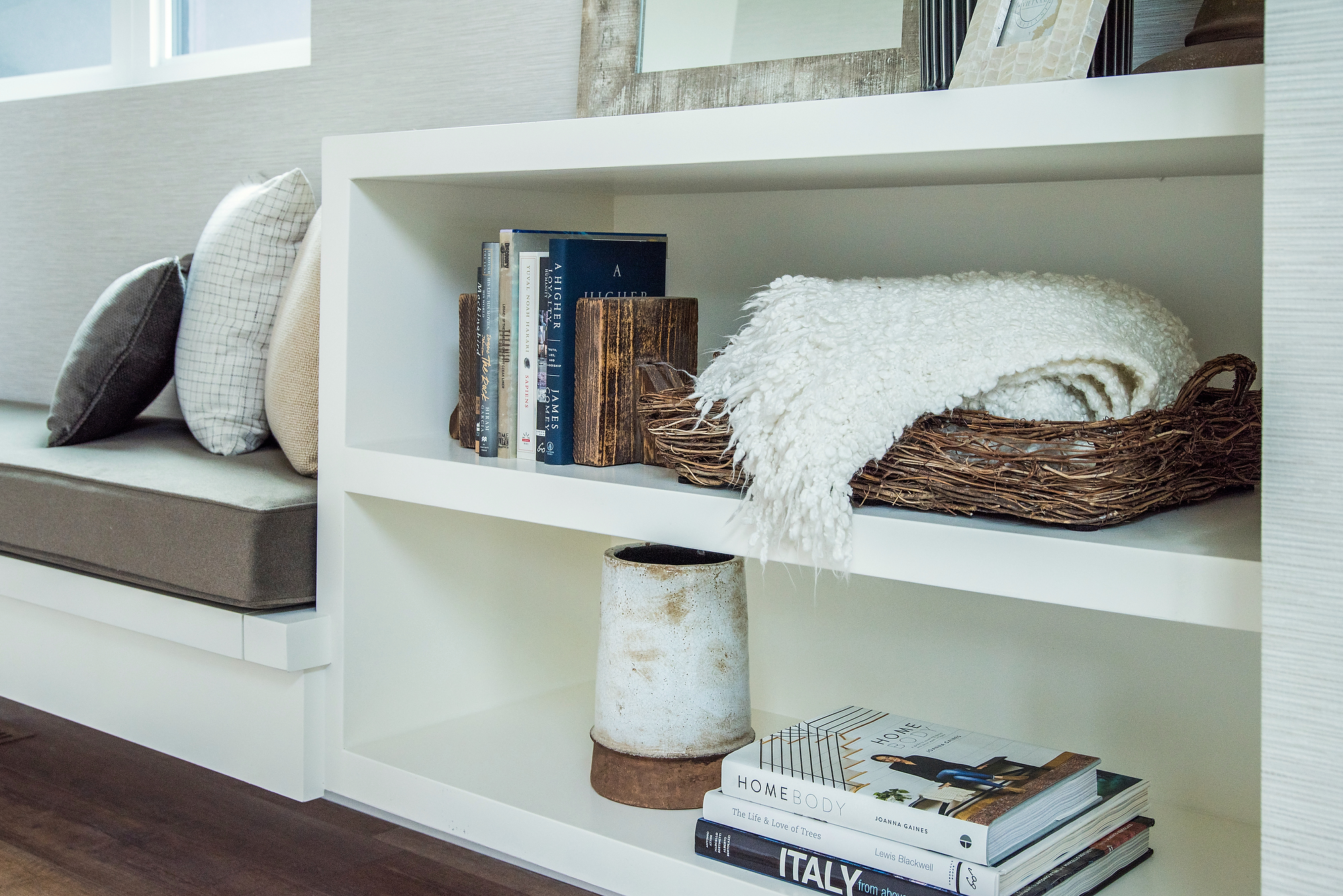 Personal decorative objects such as books, a blanket and a basket of clients used to interior style and decorate a reading niche in their new home.